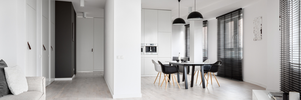 Panorama of spacious black and white apartment with many windows with long black blinds